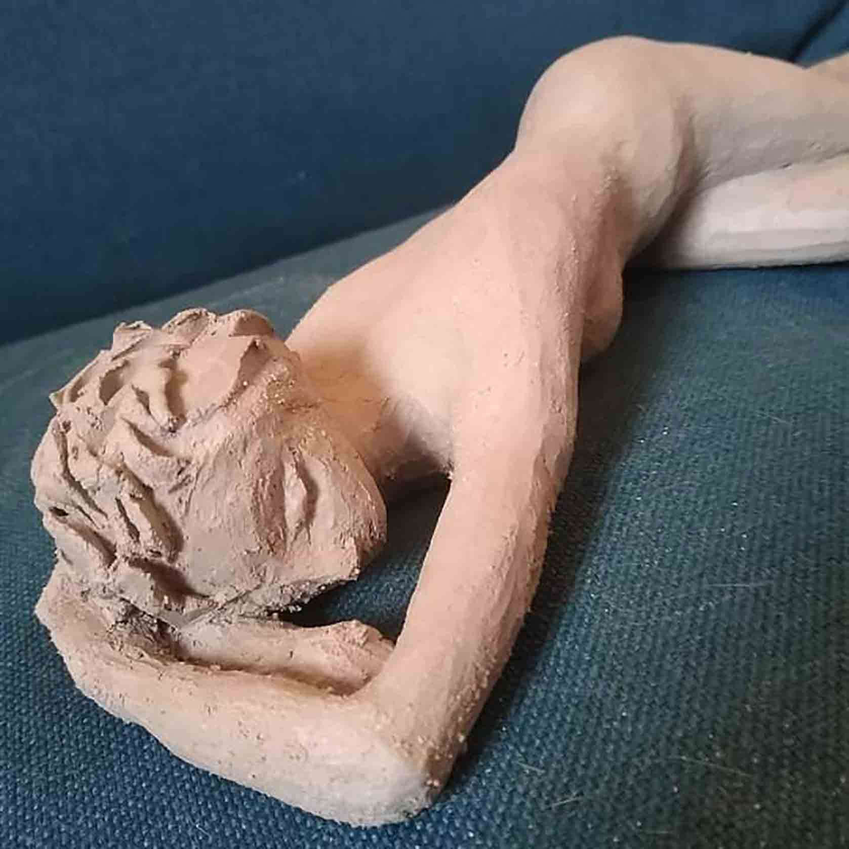 Le corps d'une femme allongée sculpté en terre par Béatrice, ancienne patiente du cancer, qui se soigne par l'art