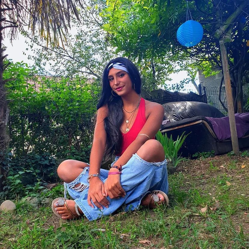 Photo de Carla assise dans l'herbe, après un cancer où elle a été entourée par les siens, présents pour accompagner leur proche