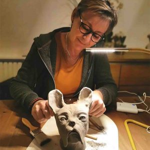 Photo de Béatrice, ancienne patiente du cancer, en pleine action de sculpter, une forme d'art-thérapie